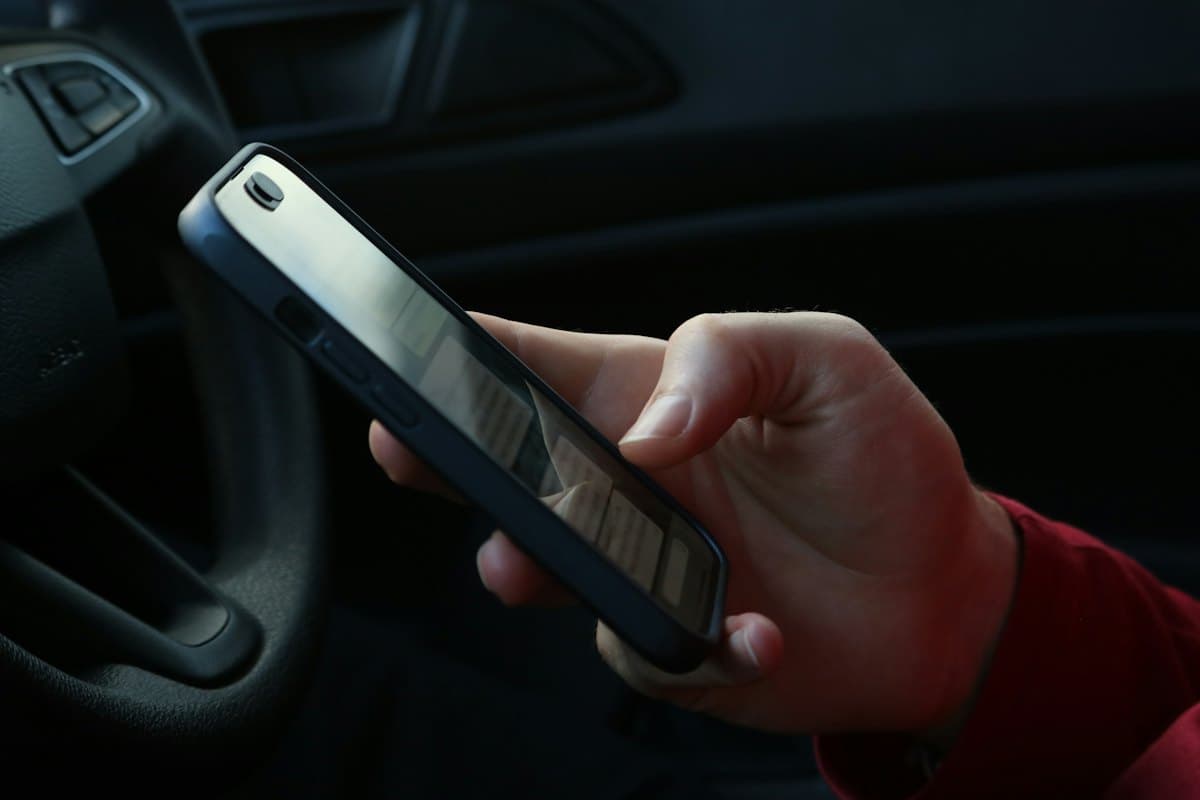 Mão segurando um smartphone dentro de um carro